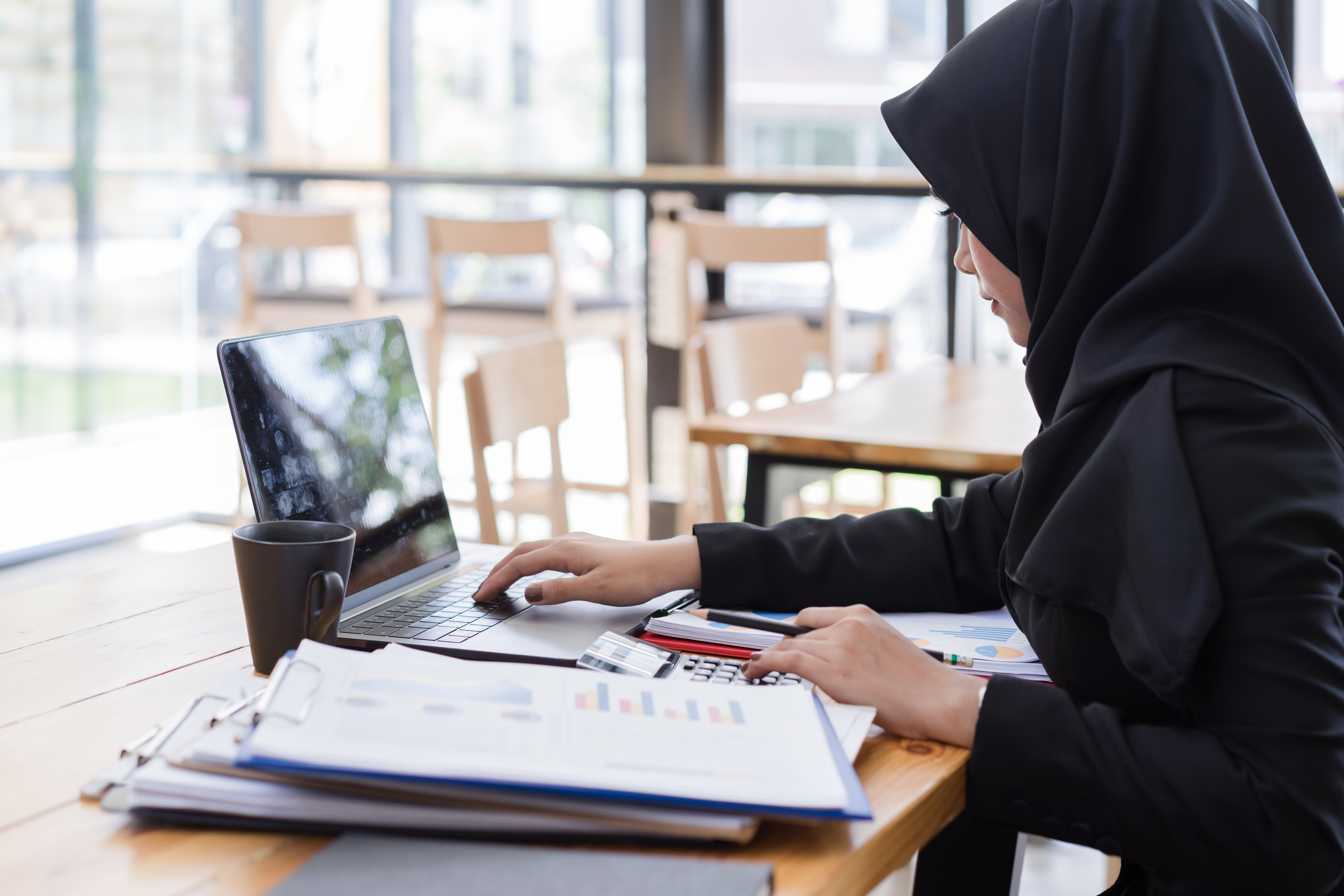 Muslim business people wearing black hijab,working in coffee shop.